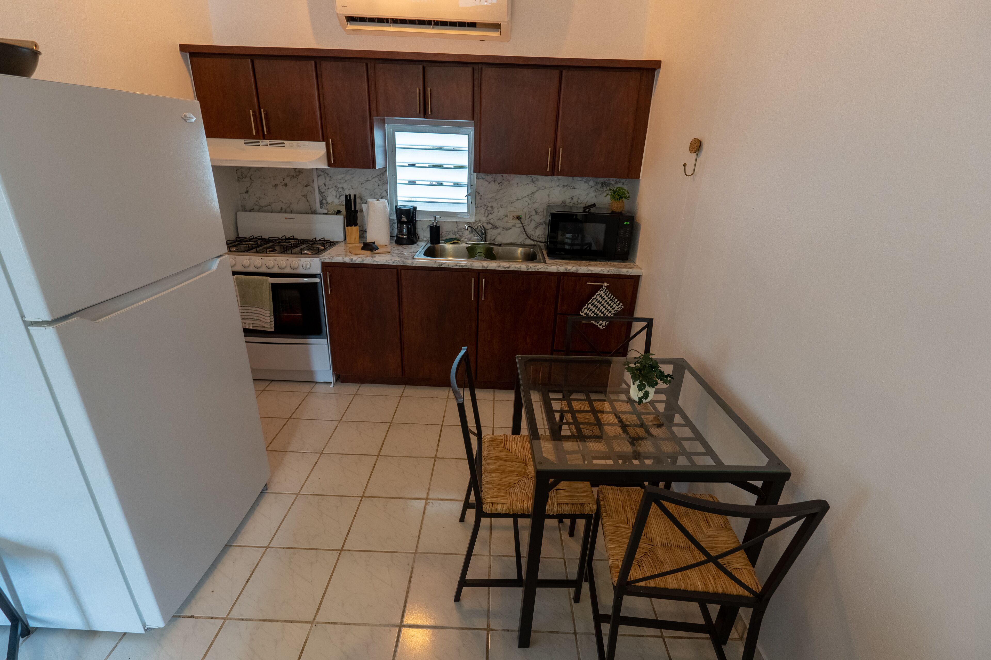 Une cuisine compacte avec des meubles en bois, un réfrigérateur blanc, une cuisinière et un coin repas comprenant une table et des chaises.