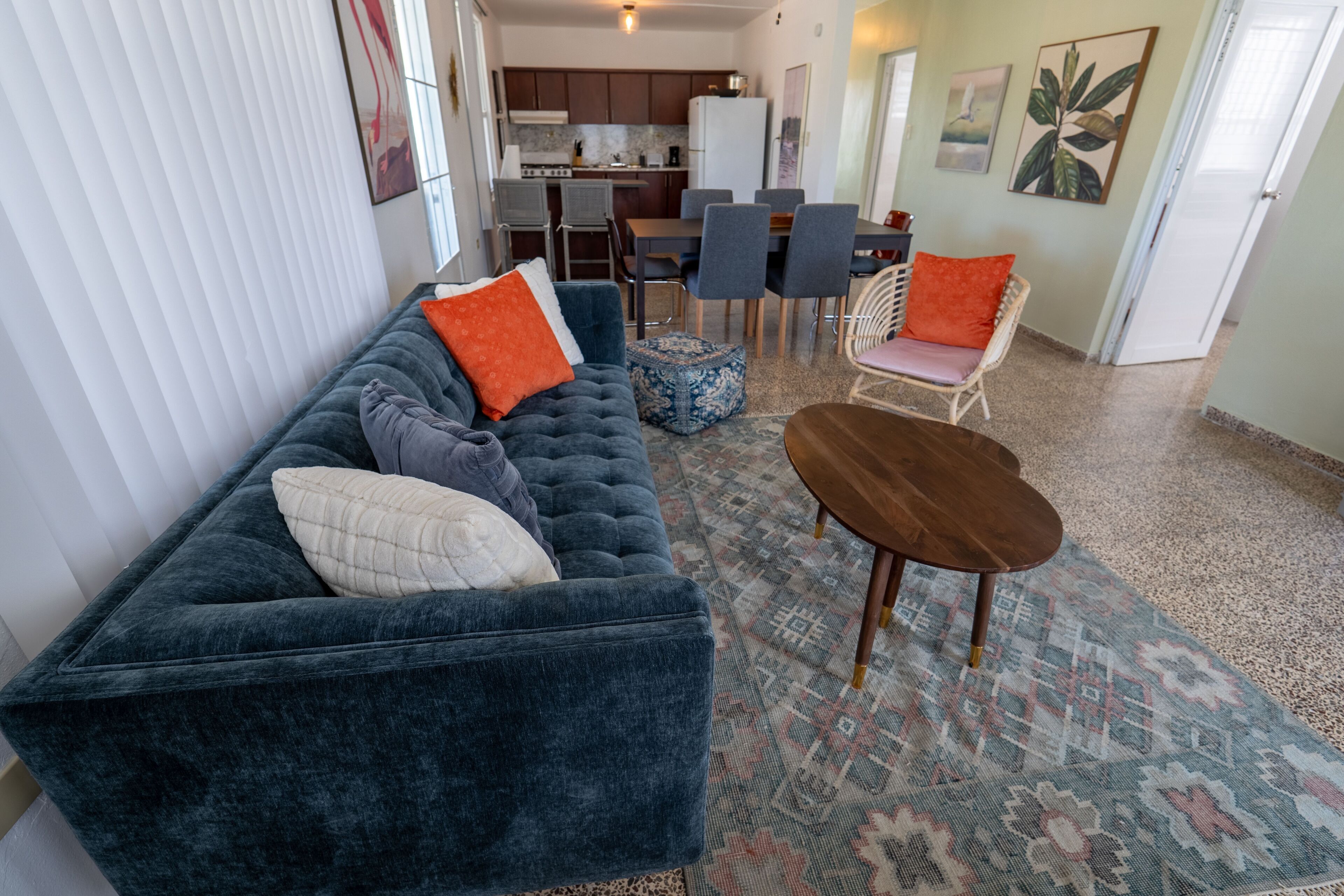 Un salon avec un canapé bleu foncé, une table basse en bois et un tapis à motifs.