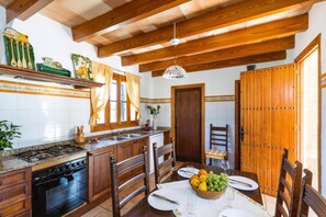 Uma cozinha com armários de madeira, um fogão e uma mesa de jantar posta com pratos e uma fruteira.