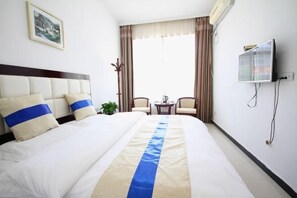 Una habitación de hotel con una cama grande, televisión, una mesita y dos sillas.
