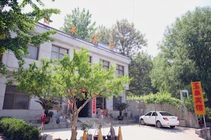 A building with a traditional architectural style, a tree in the foreground, and a parked car.