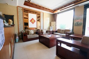 A living room with a sofa set, a coffee table, and a TV. - Yuquan Hotel (Huayin)