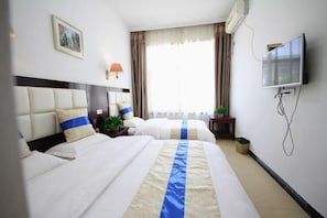 Una habitación de hotel con dos camas, televisión, un cuadro y una ventana con cortinas.