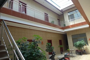 Un atrio de varios niveles con una escalera, plantas en macetas y una zona de estar.
