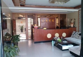 Zona de recepción de un hotel con un mostrador de madera, un sofá y una mesa de centro.