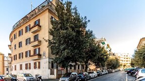 A street lined with parked cars and a building with multiple windows and balconies. - Saint Peter House Station Deluxe (Roma)