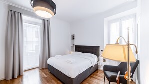 A modern hotel room with a large bed, a bedside table, a lamp, and a chair. - Saint Peter House Station Deluxe (Roma)