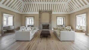 A spacious living room with two white sofas, a central coffee table, and a stone fireplace. - Quinta do Pinhô - Tarouca (Tarouca)
