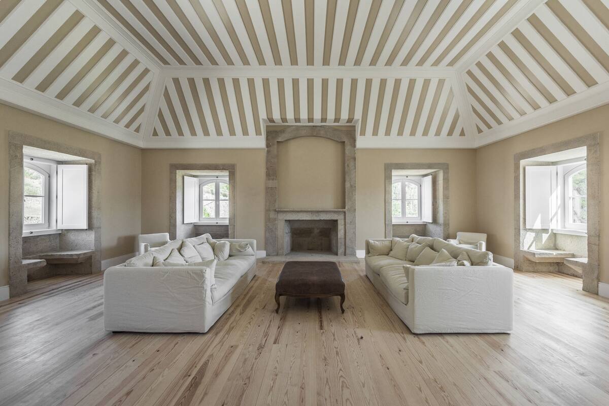 A spacious living room with two white sofas, a central coffee table, and a stone fireplace.
