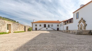 A courtyard with a white building featuring a red-tiled roof, stone walls, and a central staircase leading to the entrance. - Quinta do Pinhô - Tarouca (Tarouca)