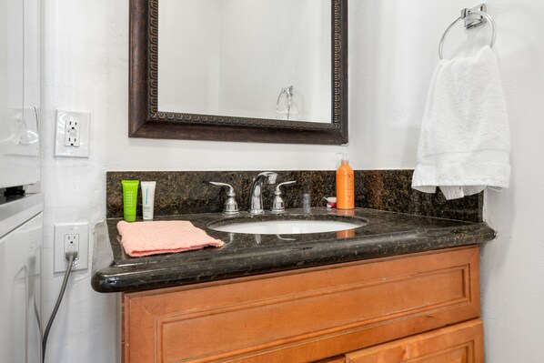 A bathroom with a sink, mirror, and towel rack.