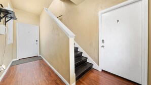 Ein Flur mit Holzboden, einer weißen Tür mit einer Nummer und einer Treppe mit weißer Geländer.