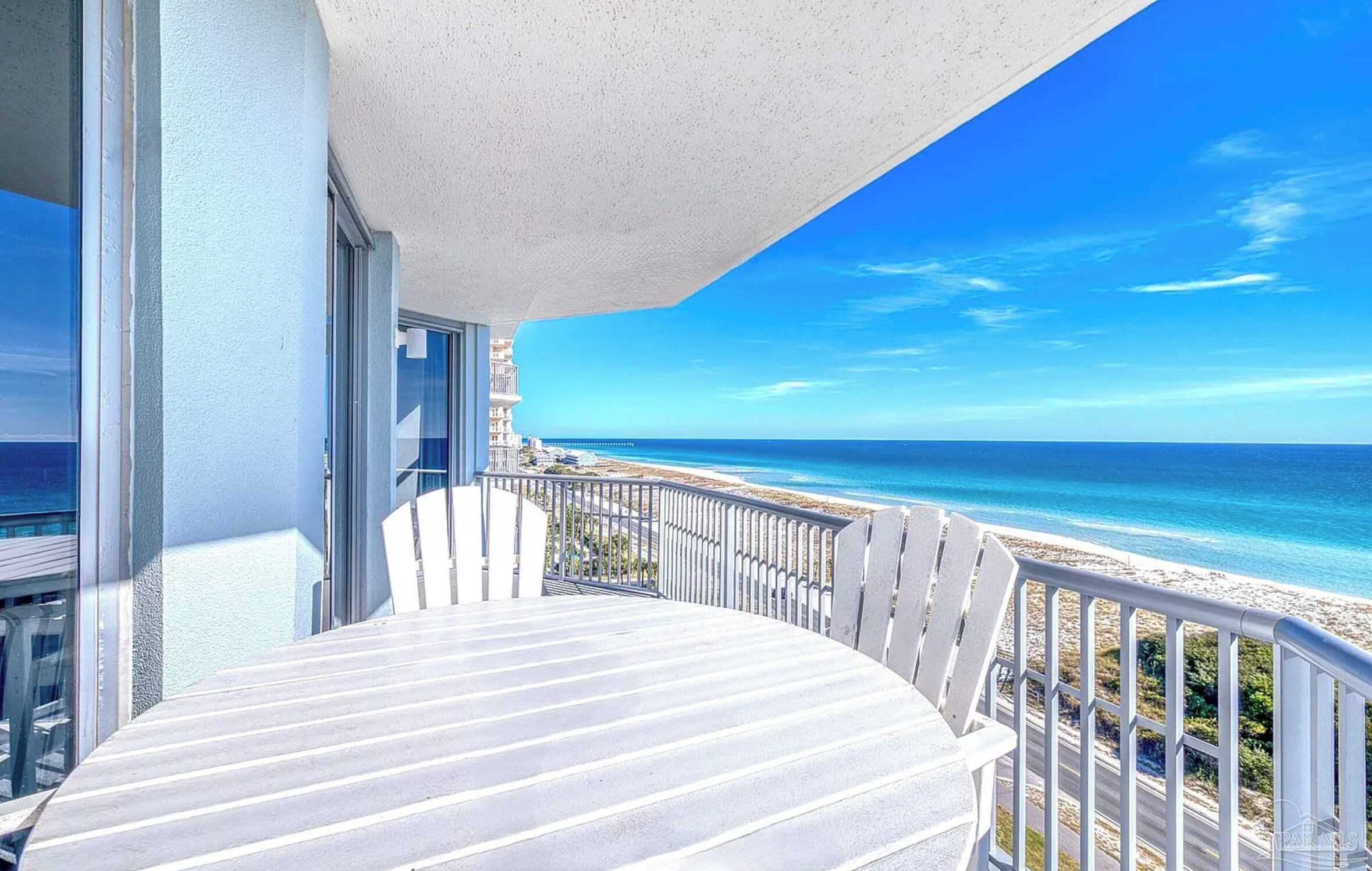 A balcony with a view of the ocean and a beach.