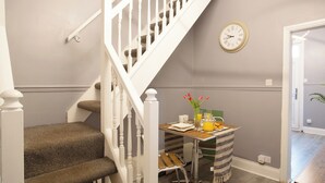 Un escalier avec une rampe blanche, une table à manger avec des aliments pour le petit-déjeuner et une horloge murale.