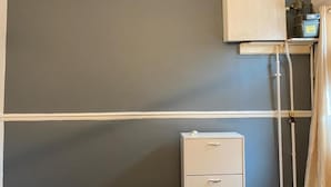 A room with a grey wall, a white cabinet, and a white filing cabinet.