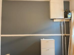A room with a grey wall, a white cabinet, and a white filing cabinet.