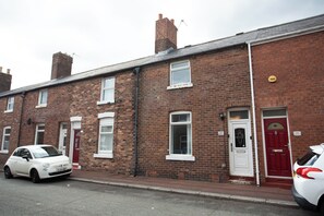 A row of terraced houses with a red door and a white car parked in front.