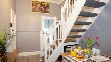 A staircase with white balusters, a dining area with breakfast items, and a wall-mounted picture.