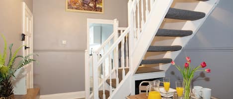 A staircase with white balusters, a dining area with breakfast items, and a wall-mounted picture.