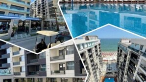 Ein modernes Hotel mit mehreren Etagen, einem zentralen Schwimmbad und Blick auf den Strand.