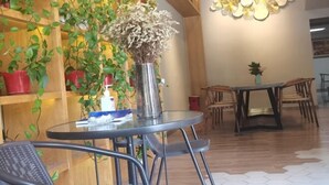 A dining area with a round glass table, metal chairs, and a vase with dried flowers. - Fuxin Inn (Zhuhai Baitengtou ) (Zhuhai)