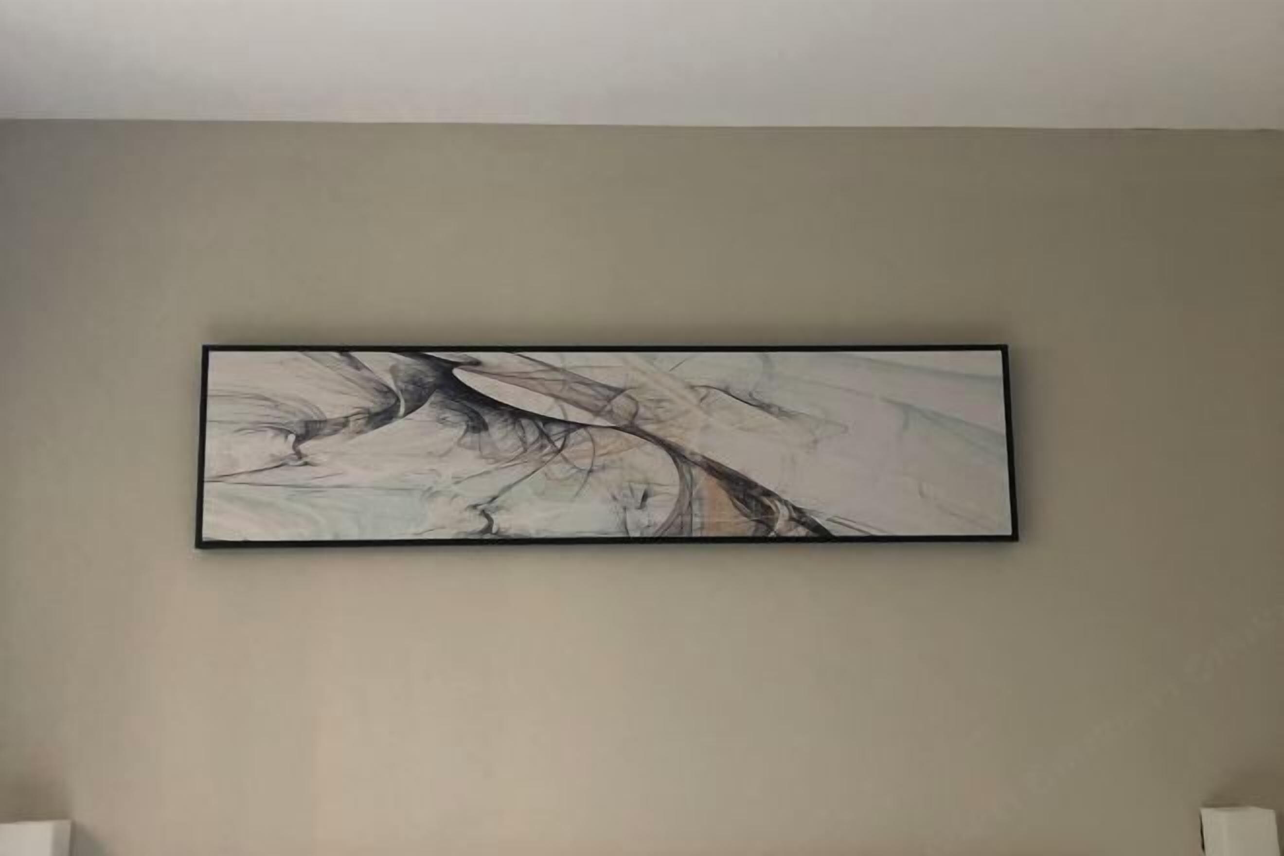 A framed abstract painting on a plain wall.