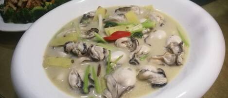 A bowl of soup with mushrooms and green vegetables on a table.