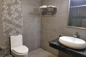A bathroom with a toilet, a sink, and a shower. - Fuxin Inn (Zhuhai Baitengtou ) (Zhuhai)