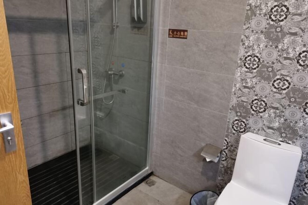 A bathroom with a glass-enclosed shower, a toilet, and patterned wall tiles.