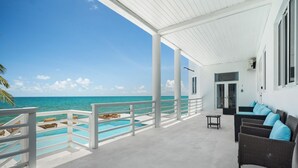 Ein überdachter Außenbereich mit Pool, Liegestühlen und Meerblick.