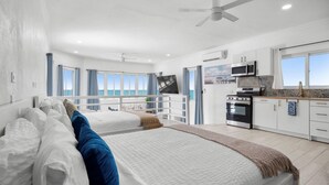 Ein Schlafzimmer mit zwei Betten, einer Küchenzeile, einem Deckenventilator und Meerblick.
