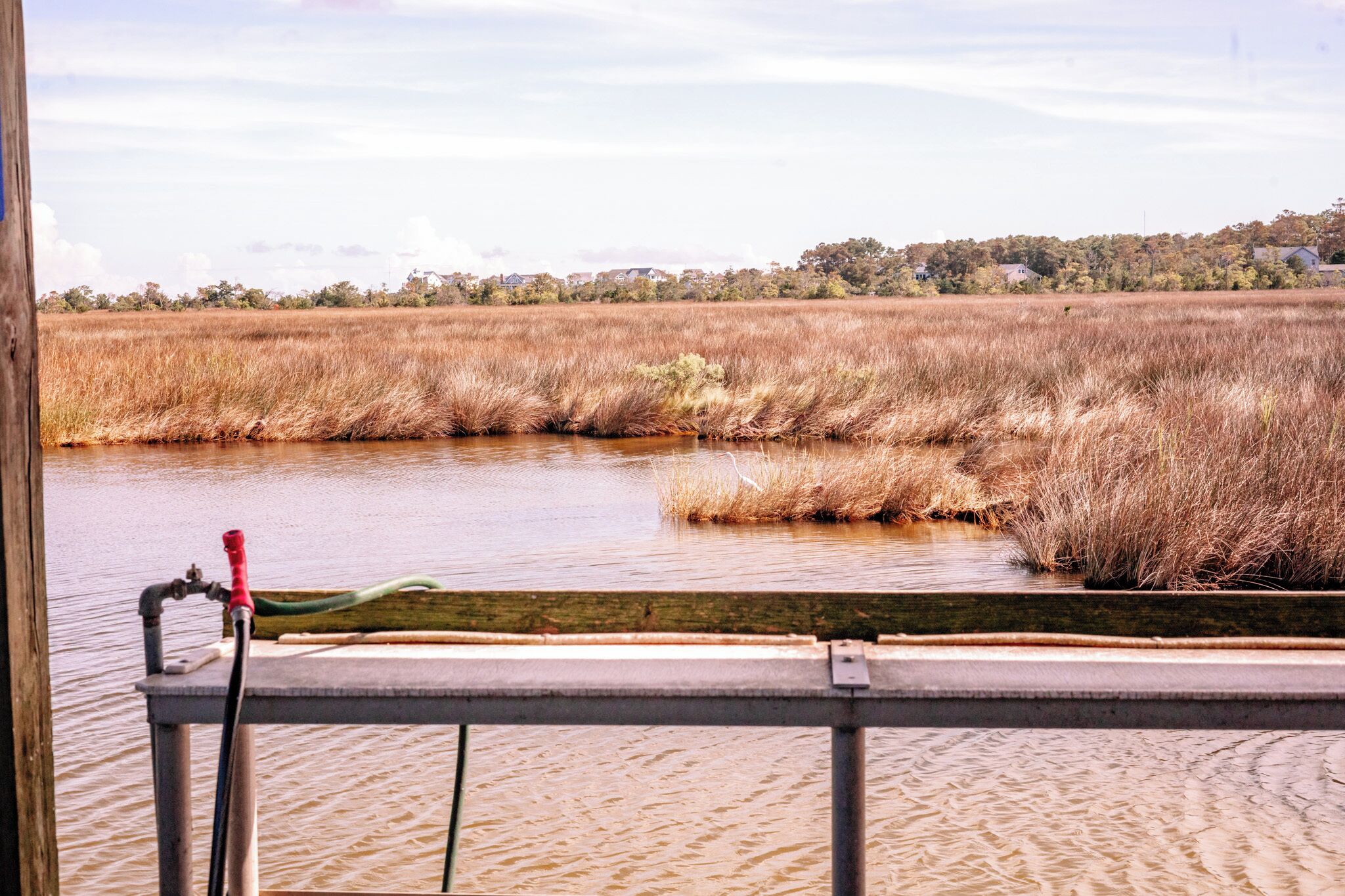 A view of a marshland with a wooden dock and a water pump.