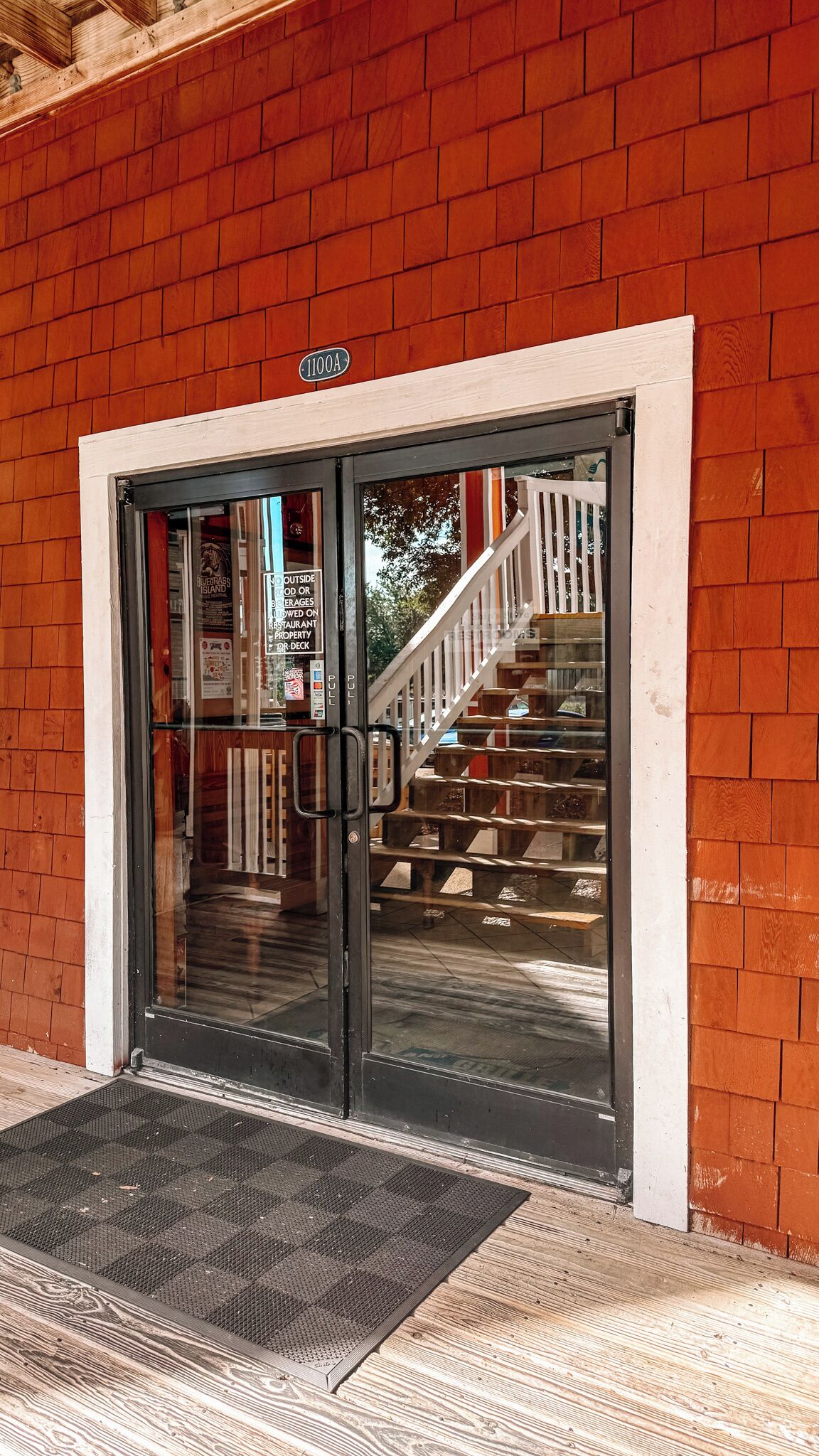 A building entrance with a black door, a white frame, and a sign above the door.