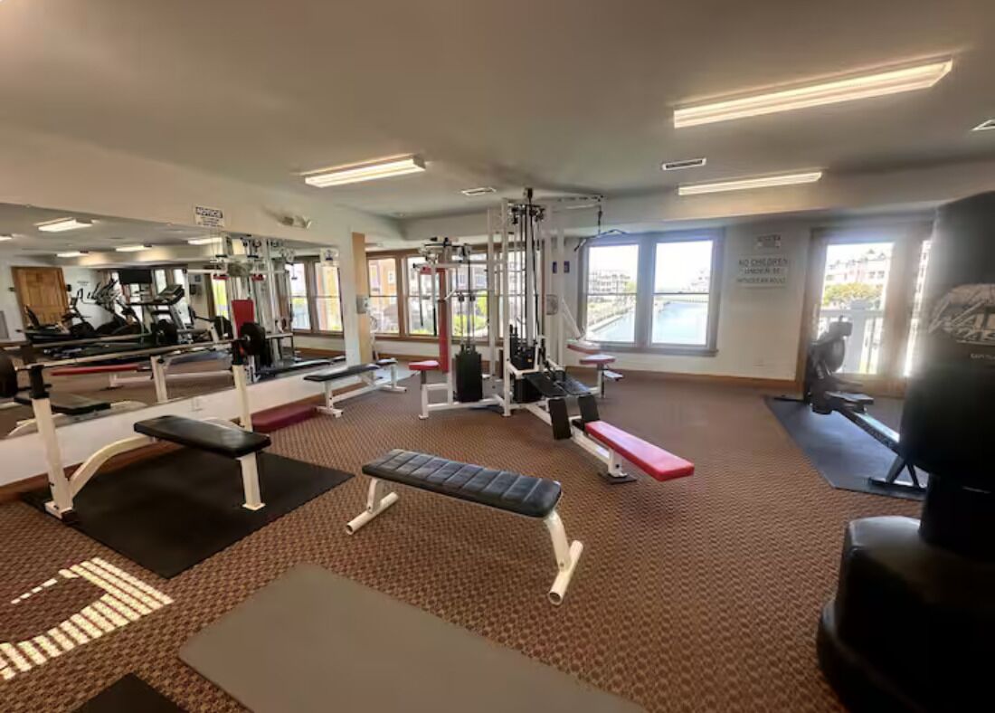 A gym with various exercise equipment, including treadmills, weight machines, and benches.