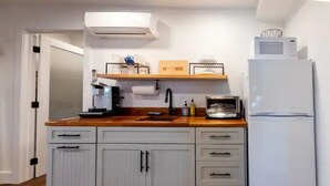 A compact kitchen with white cabinets, a microwave, and a refrigerator. - The Recovery Room-0.5 Mi to Beach & 0.3 to Sound (Kill Devil Hills)
