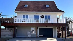Una casa a due piani con garage, un balcone e un piccolo portico.