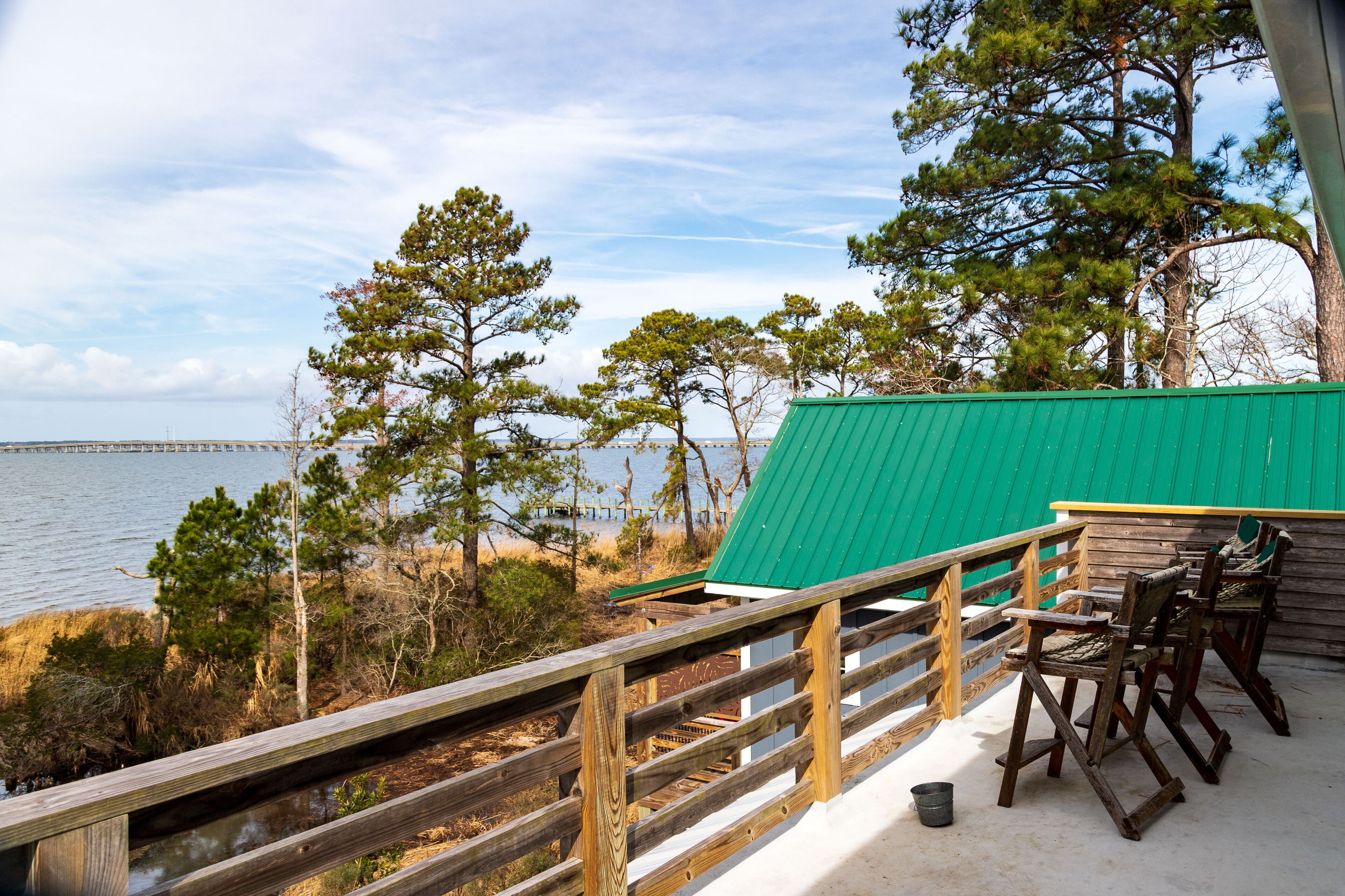 A wooden deck with a green roof overlooking a body of water and trees.