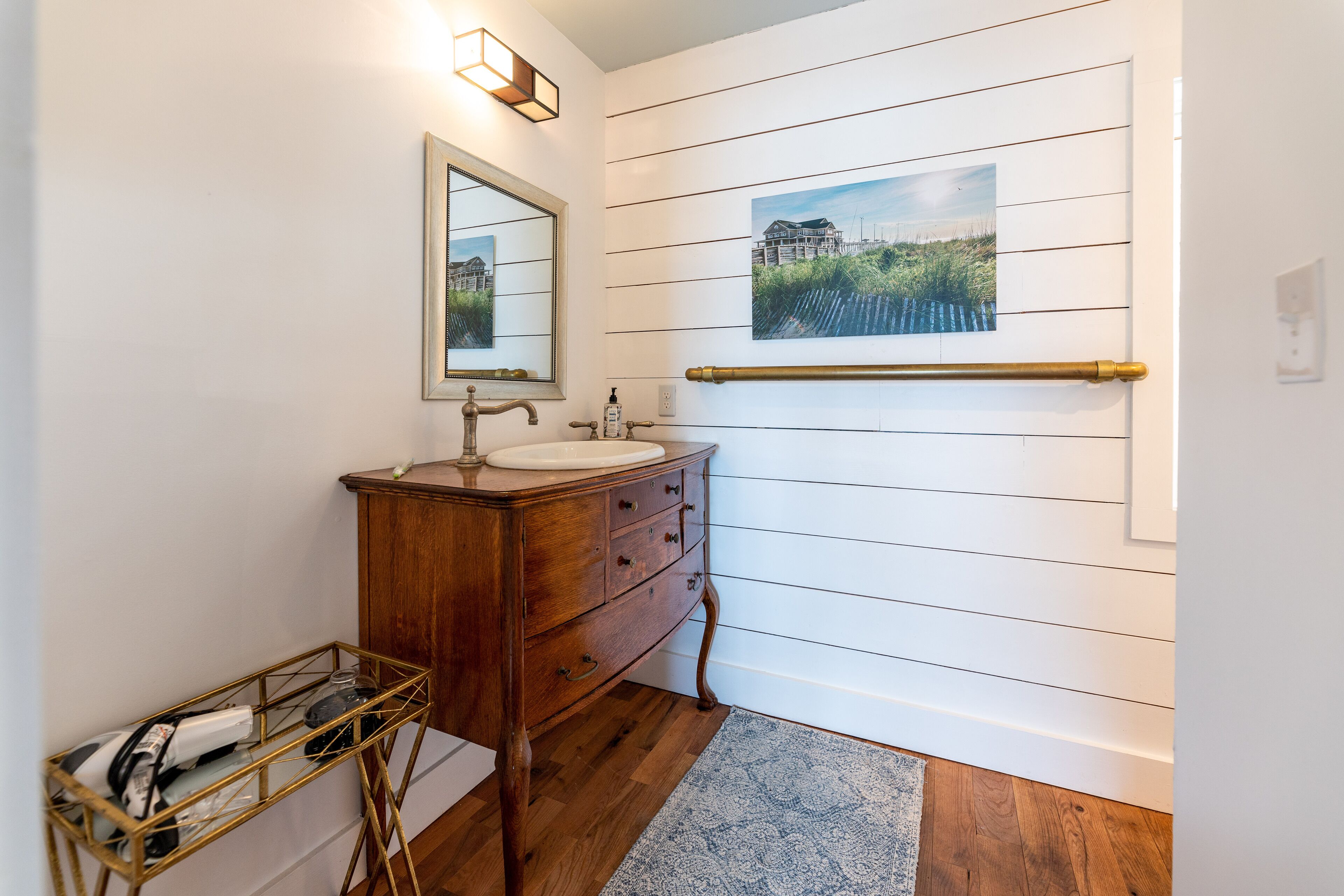 A bathroom with a wooden vanity, a mirror, a sink, and a towel rack.