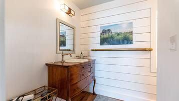 A bathroom with a wooden vanity, a mirror, a sink, and a towel rack.
