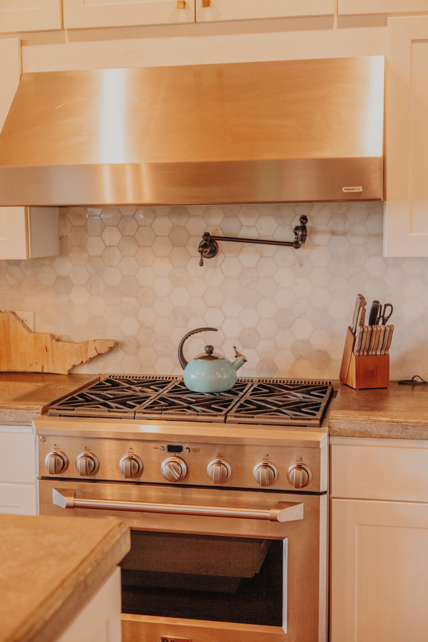 A kitchen with a stainless steel stove, an oven, and a hexagonal tile backsplash.