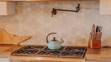 A kitchen with a stainless steel stove, an oven, and a hexagonal tile backsplash.