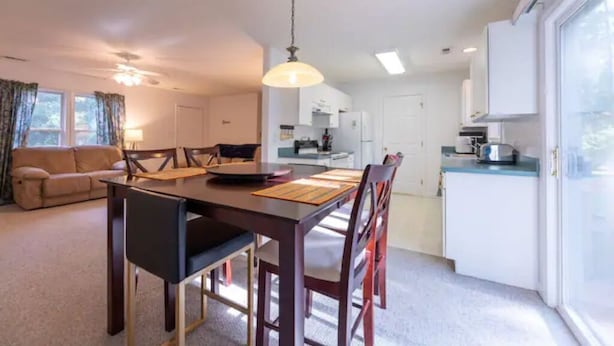 Une cuisine moderne avec des meubles blancs, une table à manger avec des chaises et une grande fenêtre.