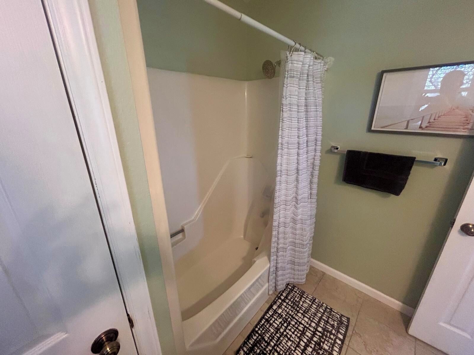 Une salle de bain avec une douche, un porte-serviettes et une porte.