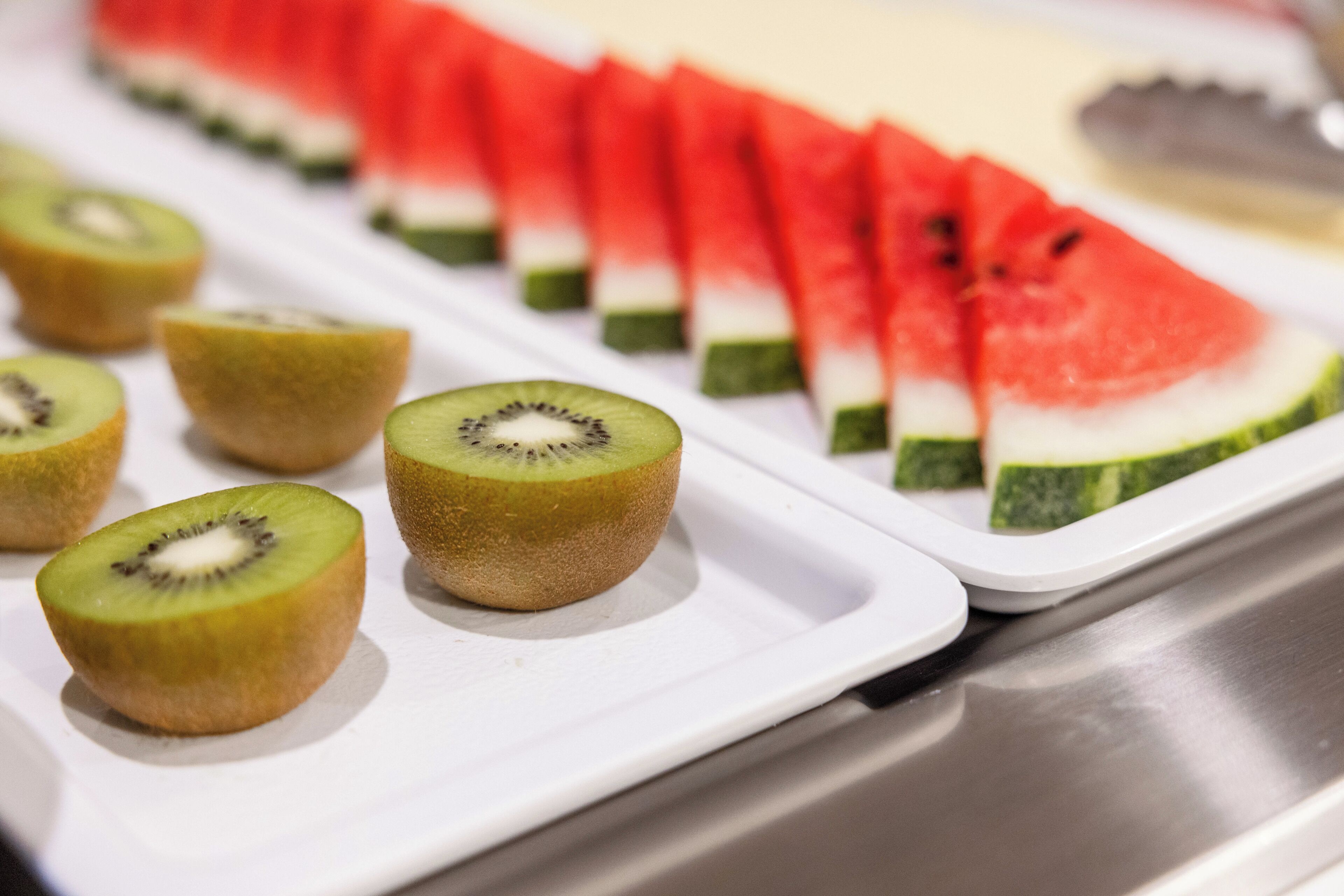 Una bandeja con sandía y kiwi en rodajas, sobre un plato blanco.