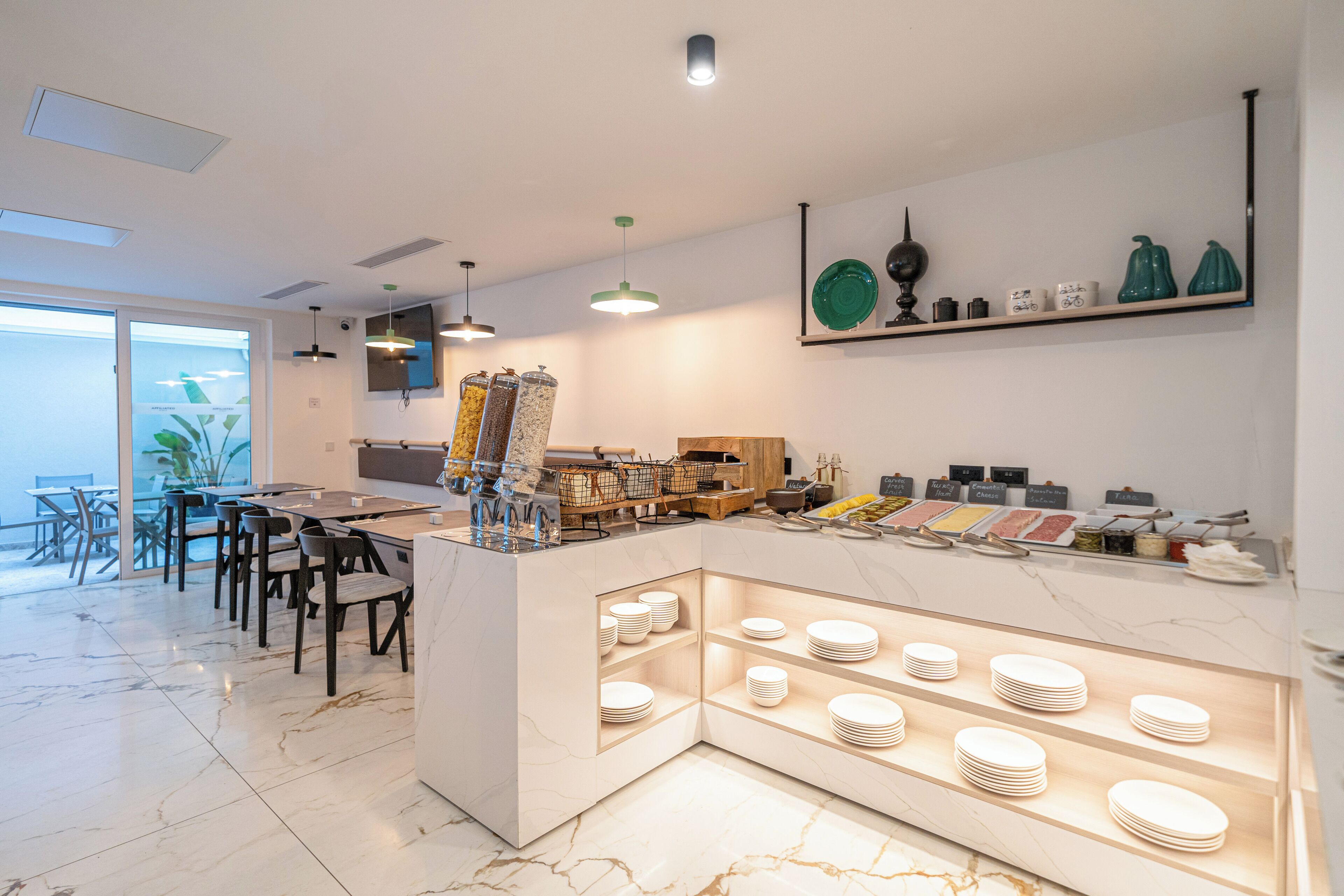 A modern dining area with a marble floor, a central island with a food display, and a seating arrangement with chairs and tables.