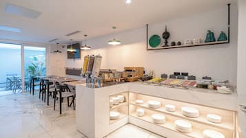 A modern dining area with a marble floor, a central island with a food display, and a seating arrangement with chairs and tables.