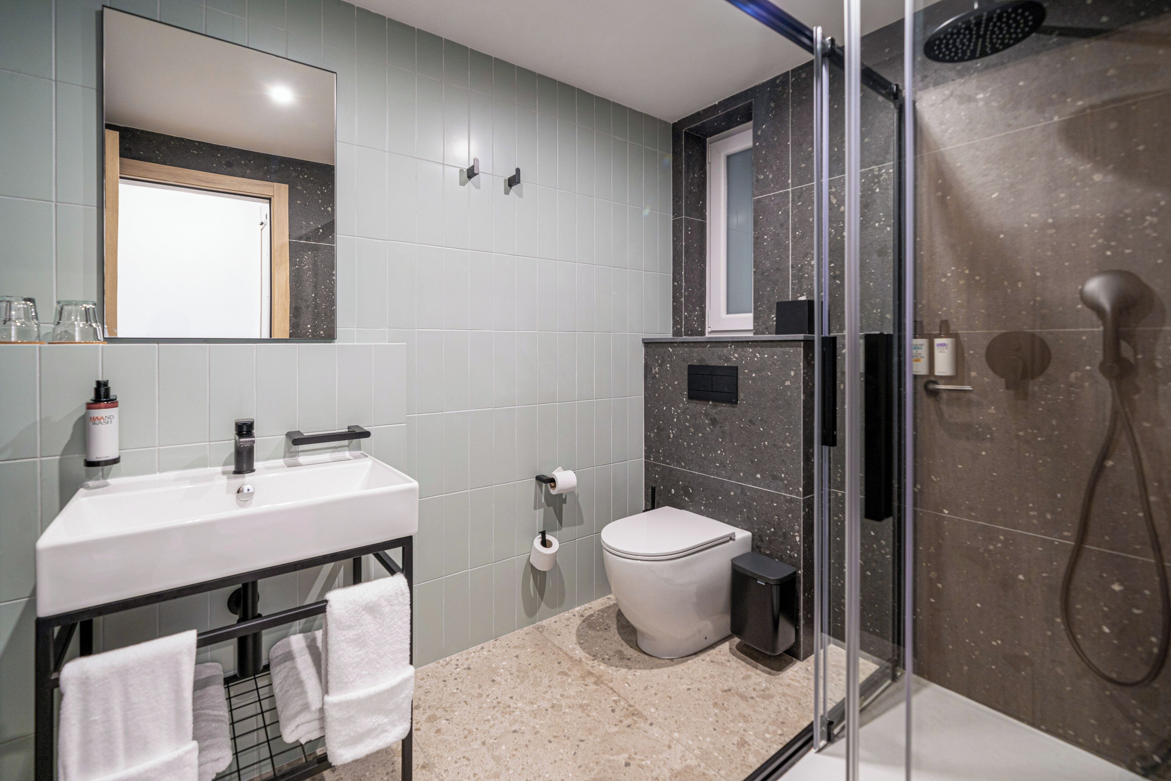 A modern bathroom with a white sink, a toilet, a glass shower enclosure, and a mirror above the sink.