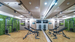A gym with mirrored walls, wooden flooring, and various exercise equipment.