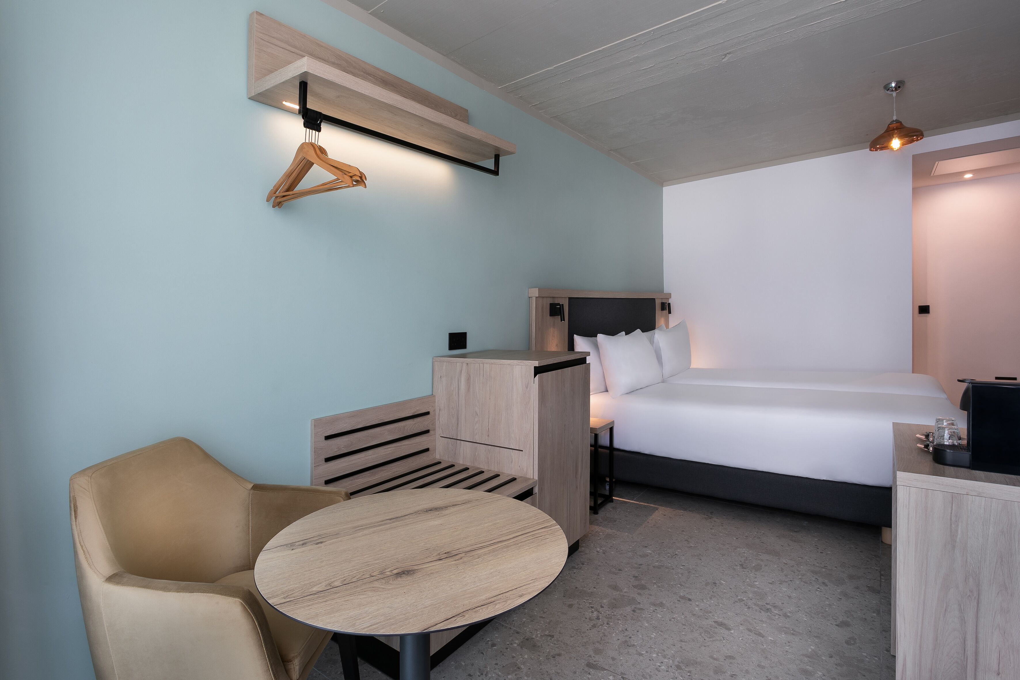 Una habitación de hotel moderna con una cama, un escritorio, una silla y una mesita.