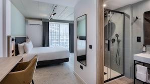 Une chambre d’hôtel équipée d’un lit, d’un bureau, d’une chaise, d’une douche et d’une salle de bain avec un lavabo.